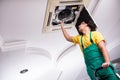 The young repairman repairing ceiling air conditioning unit Royalty Free Stock Photo