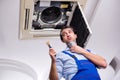 Young repairman repairing ceiling air conditioning unit Royalty Free Stock Photo