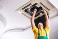 Young repairman repairing ceiling air conditioning unit