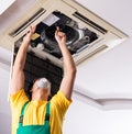 Young repairman repairing ceiling air conditioning unit Royalty Free Stock Photo