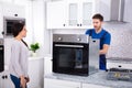 Young Repairman Repairing Oven On Kitchen Worktop Royalty Free Stock Photo