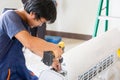 Young repairman team fixing air conditioner unit, Asian technician man installing an air conditioning in a client house, Royalty Free Stock Photo