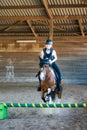 Pretty young girl doing equestrian show jumping on her pony in a farm Royalty Free Stock Photo