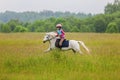 Young rider galloping on horseback across the field Outdoors