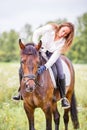 Young rider girl bent to horse for complimenting