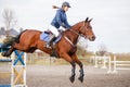 Young rider girl at show jumping. Jump hurdle