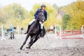 Young rider man galloping on bay horse in autumn