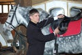 Young rider tightens a saddle-girth Royalty Free Stock Photo