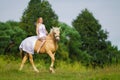 Rider woman blonde with long hair in a white dress with a train posing on a palamino horse Royalty Free Stock Photo