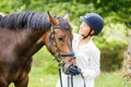 Young rider woman in helmet holding bay horse