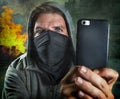 Young rioter filming street chaos . ultra and radical man masked recording riot video on mobile phone during violent turmoil