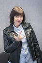 Young rock Girl in leather jacket. Punk is not dead. Girl making horn sign hand gesture. Cheerful woman rock lover