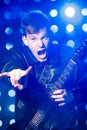 Young rock musician playing electric guitar and and making rock gesture. Rock star on background of spotlights Royalty Free Stock Photo