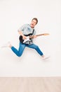 Young rocker playing on electro guitar, showing tongue and jumping Royalty Free Stock Photo