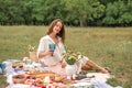 Young romantic brunette woman enjoy outdoor picnic on green lawn and hold glass of white wine Royalty Free Stock Photo