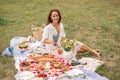 Young romantic brunette woman enjoy outdoor picnic on green lawn and hold glass of white wine Royalty Free Stock Photo
