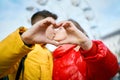 Young romantic couple on date, embracing and kissing through a heart gesture made with their fingers, spending time