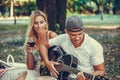 Young romantic couple having fun with guitar during picnic in the park Royalty Free Stock Photo