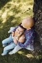 Young romantic couple in love spend time in the park, sits on a lawn under a tree. Young man tenderly embracing young Royalty Free Stock Photo