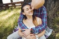 Young romantic couple in love spend time in the park, sits on a lawn under a tree. Young man tenderly embracing young Royalty Free Stock Photo