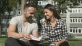 Young romantic couple sitting in park and reading book.