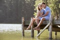 Young Romantic Couple Sitting On Wooden Jetty Looking Out Over L Royalty Free Stock Photo