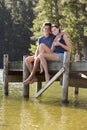 Young Romantic Couple Sitting On Wooden Jetty Looking Out Over L Royalty Free Stock Photo