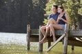 Young Romantic Couple Sitting On Wooden Jetty Looking Out Over Lake Royalty Free Stock Photo