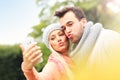 Young romantic couple with smartphone in the park in autumn Royalty Free Stock Photo