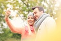 Young romantic couple with smartphone in the park in autumn Royalty Free Stock Photo