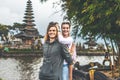 Young romantic couple of trourists on the Ulan Danu temple background. Bali island.