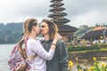 Young romantic couple of trourists on the Ulan Danu temple background. Bali island.