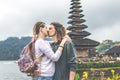 Young romantic couple of trourists on the Ulan Danu temple background. Bali island.