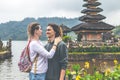 Young romantic couple of trourists on the Ulan Danu temple background. Bali island.