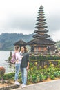 Young romantic couple of trourists on the Ulan Danu temple background. Bali island.