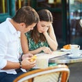 Young romantic couple using map in a cozy outdoor cafe in Paris, France Royalty Free Stock Photo