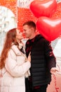 Young romantic couple in warm clothes. A man holds heart-shaped balloons in his hands Royalty Free Stock Photo