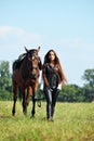 Young romantic girl leading saddle horse Royalty Free Stock Photo