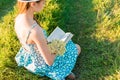 Young romantic girl reading a book sitting on the grass