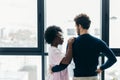 Romantic mixed race couple standing by the window thinking about their future. Royalty Free Stock Photo