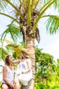 Young romatic couple tourist under the coconut palm. Bright green and yellow picture. Bali island. Indonesia.