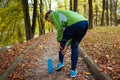 Young runner injured leg during workout exercises in autumn park. Woman feels ankle pain and crick. Body sore Royalty Free Stock Photo