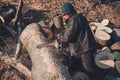 Young rural girl cut a tree chainsaw in gloves, cook firewood for winter