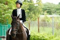 Young 20s Asian woman in horse riding suit with beautiful animal outdoors. Female ride tall smart