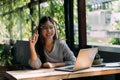 Young 20s Asian woman looking at camera while wearing a protective mask with laptop, mobile phone, and notebook for Royalty Free Stock Photo