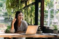 Young 20s Asian woman looking at camera while wearing a protective mask with laptop, mobile phone, and notebook for Royalty Free Stock Photo