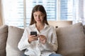 Young pretty woman using smartphone resting on sofa at home Royalty Free Stock Photo