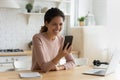 Female sit indoor holding modern smartphone laughing at online video Royalty Free Stock Photo