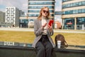 Young 30s woman walks in the park, writes a message, chat online in social network on her phone and drinks coffee in Royalty Free Stock Photo