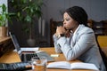 Frustrated african businesswoman looking thoughtfully at open laptop and trying to focus on work